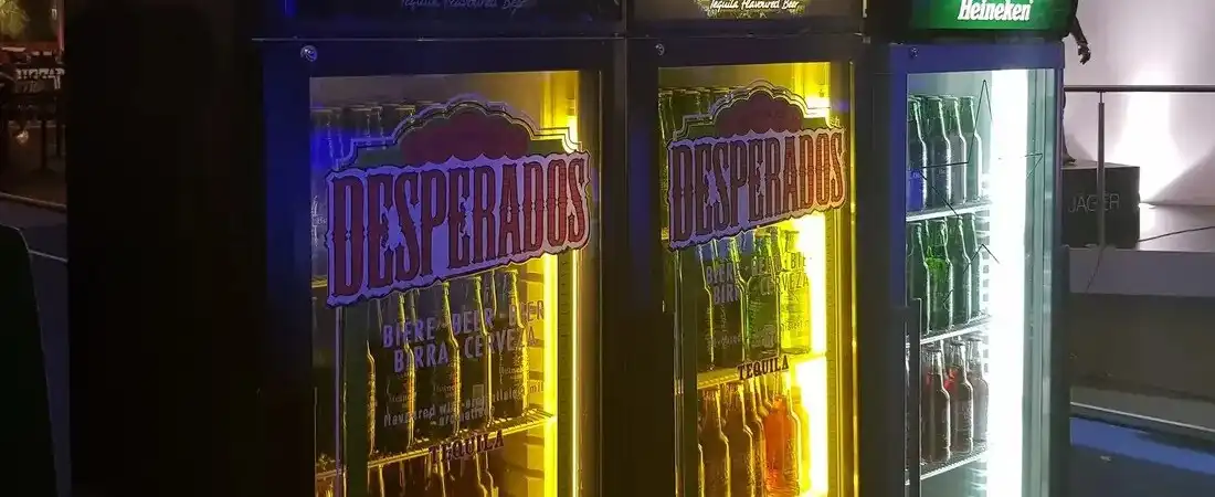 Drei beleuchtete Getränkekühlschränke auf einem Event, gefüllt mit verschiedenen gekühlten Biersorten wie Desperados und Heineken.