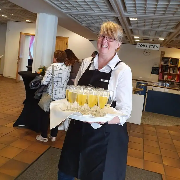 Astrid Sleboda vom Veranstaltungsservice bietet Gästen bei einem Sektempfang in Datteln frischen Sekt auf einem Tablett an.