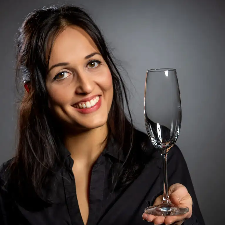 Sarah Schäfer aus dem Team der Bankettleitung stößt lächelnd mit einem Sektglas auf eine erfolgreiche Veranstaltung in NRW an.